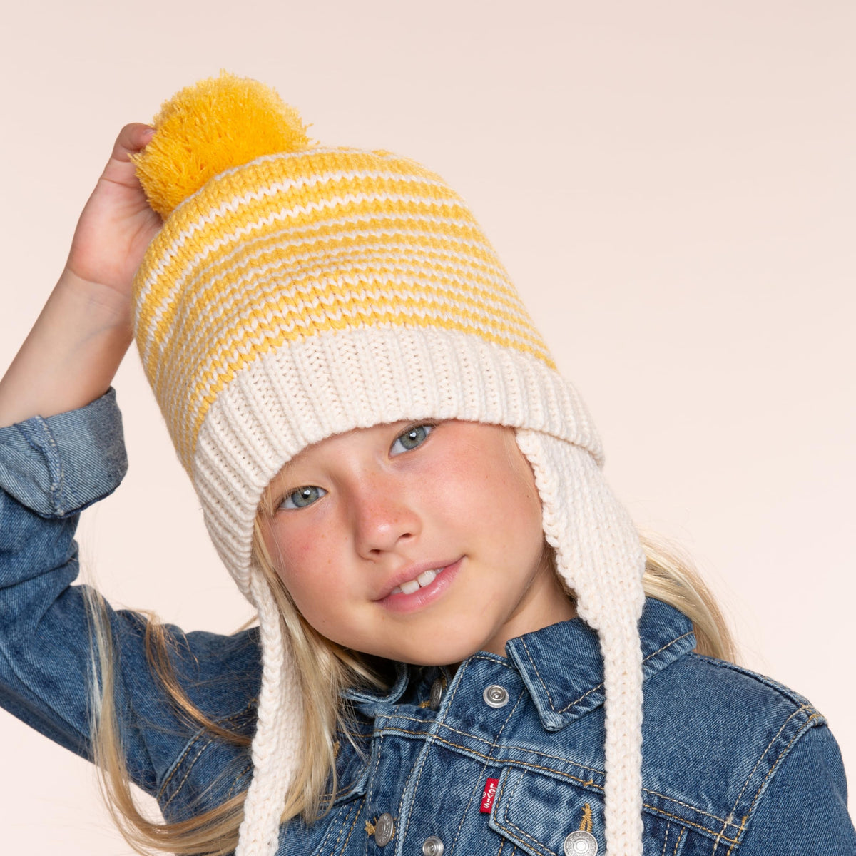 Kids knit beanie with yellow stripes, earflaps, chin ties, and top pom-pom