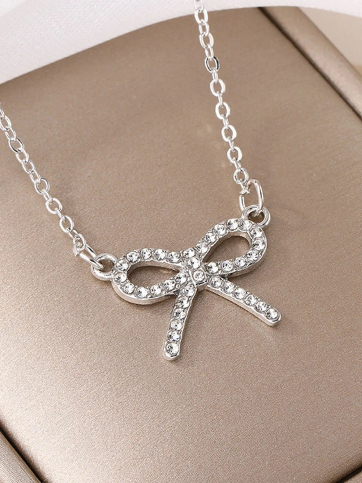 Silver bow-knot pendant necklace with clear rhinestone ribbon and oval loops