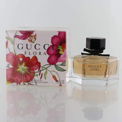 Gucci Flora perfume bottle beside floral box; clear glass with amber liquid, black top