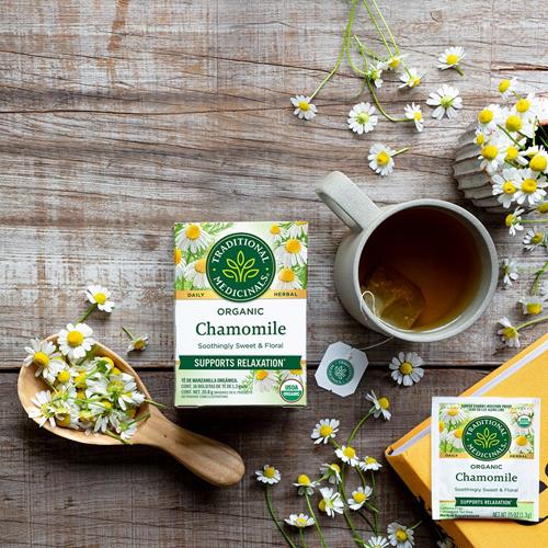 Chamomile herbal tea cup with chamomile flowers and tea box on a wooden table