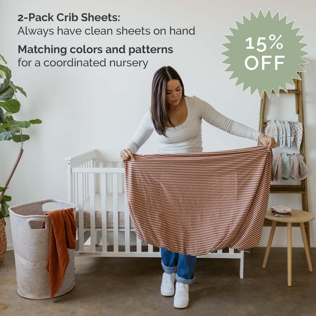 Crib sheet set with orange-and-white striped fabric, folded and held up
