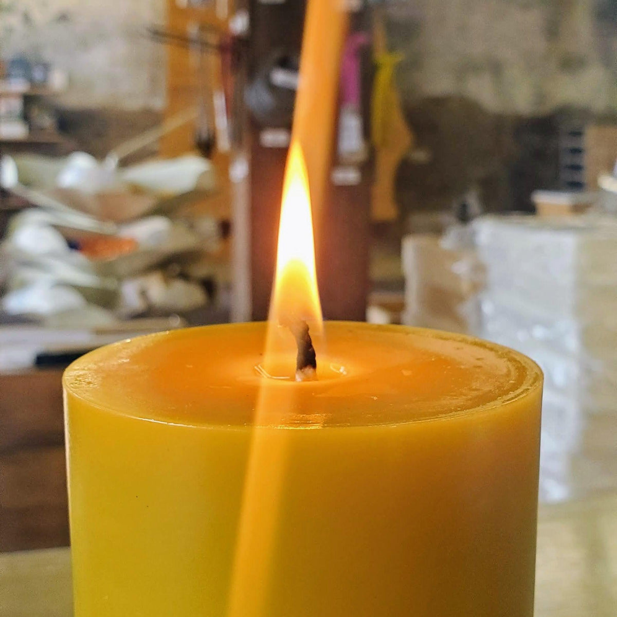 Burning yellow beeswax pillar candle with bright flame and melt pool