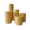 Set of yellow beeswax pillar candles with exposed wicks, various heights