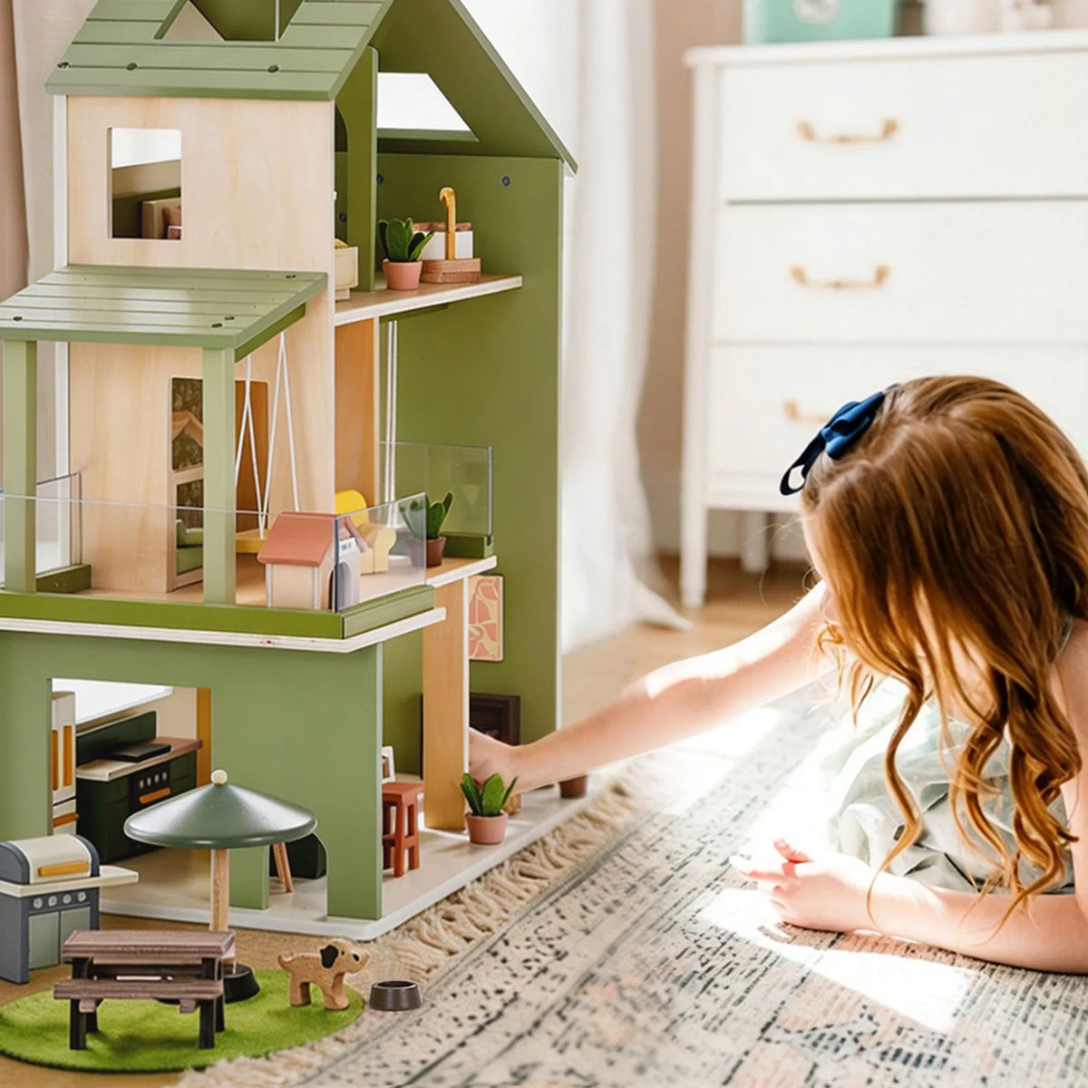 Green dollhouse playset with open floors, yellow bed, and mini furniture inside