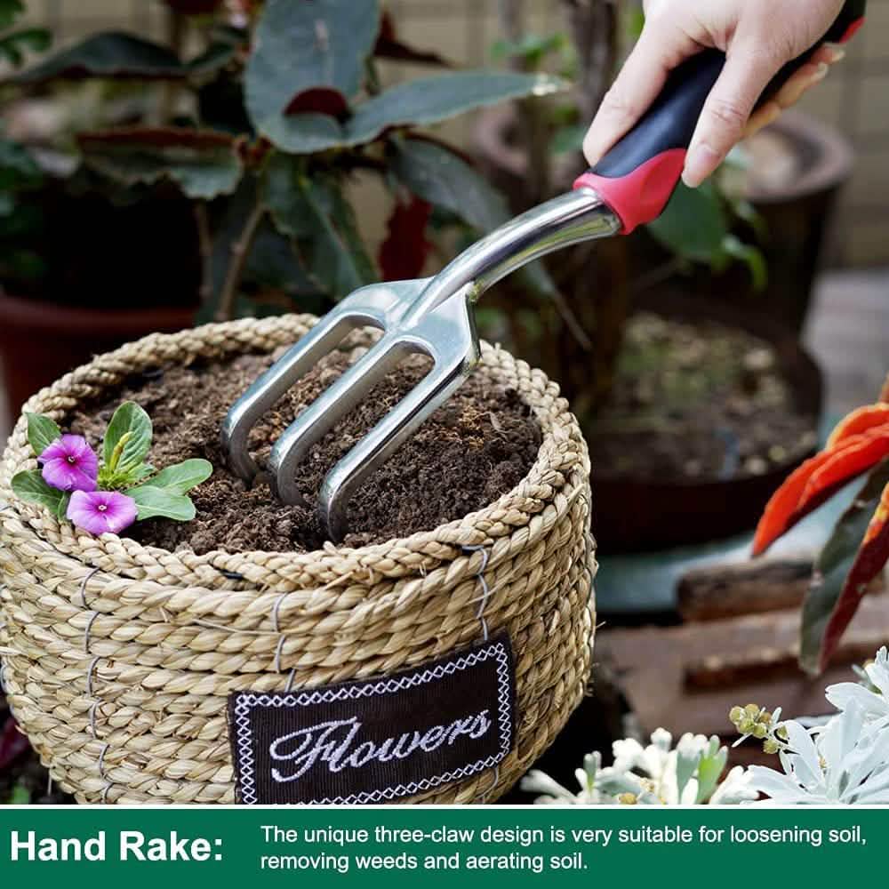 Hand rake tool with metal tines and black/red handle lifting soil from planter