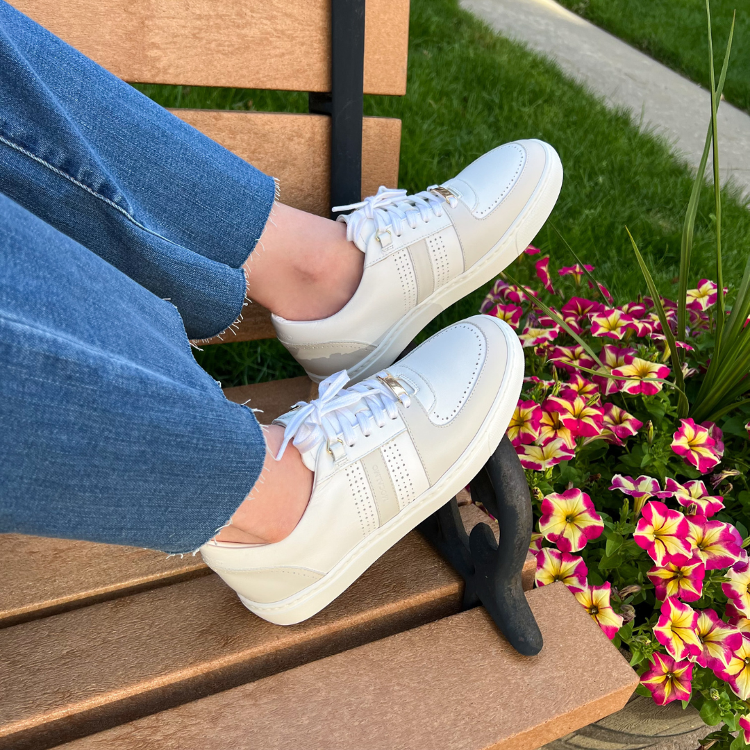 Women’s ivory and gray sneakers on feet, paired with blue jeans outdoors