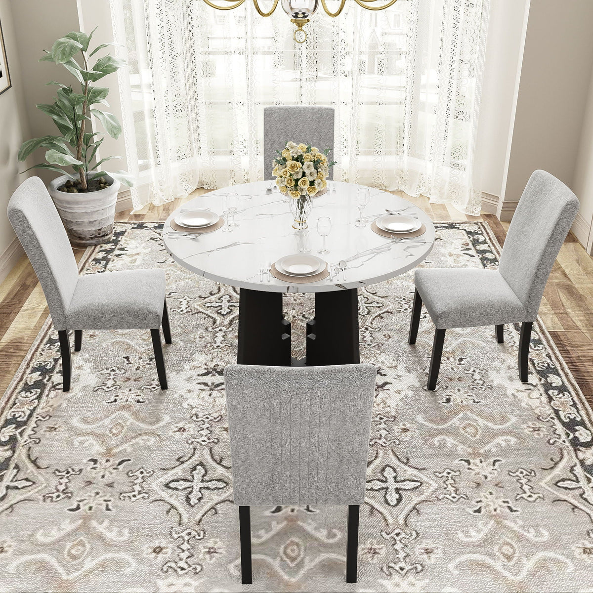 Round white marble-look dining table with four gray upholstered chairs around it