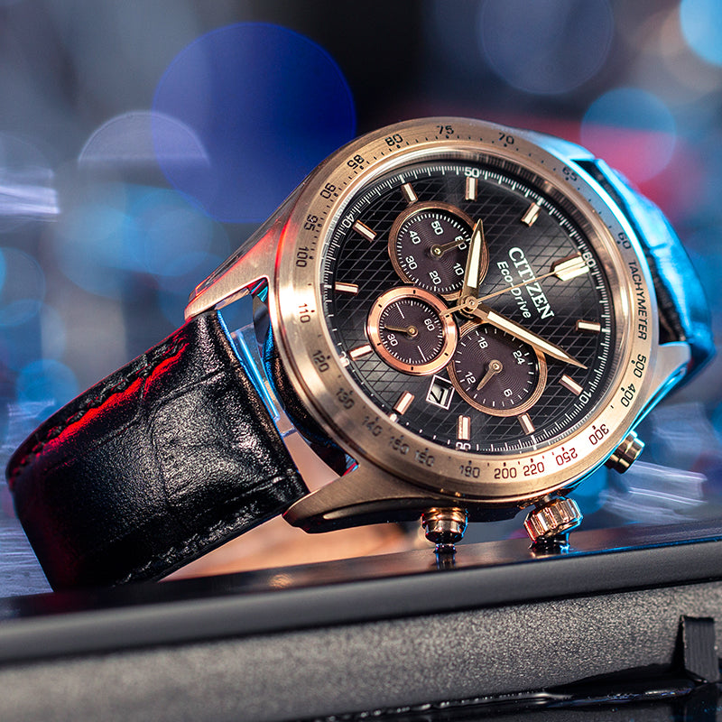 Men's chronograph watch with gold dial and black leather strap.