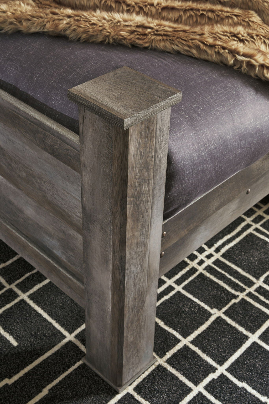 Gray wood bed post and rail with dark fabric mattress