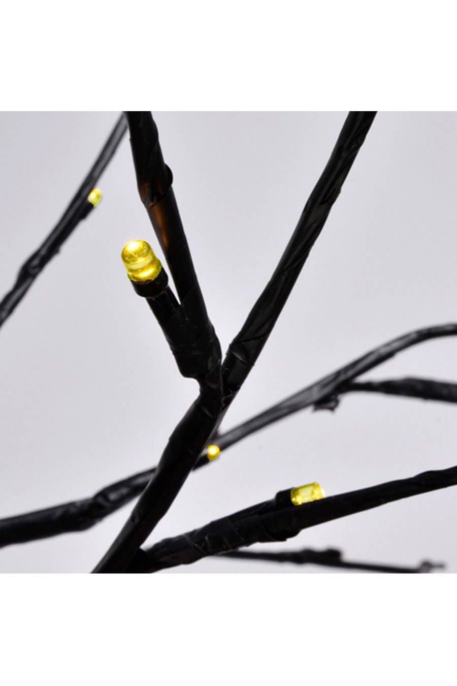 Close-up of black branch tree lights with small warm yellow LED bulbs