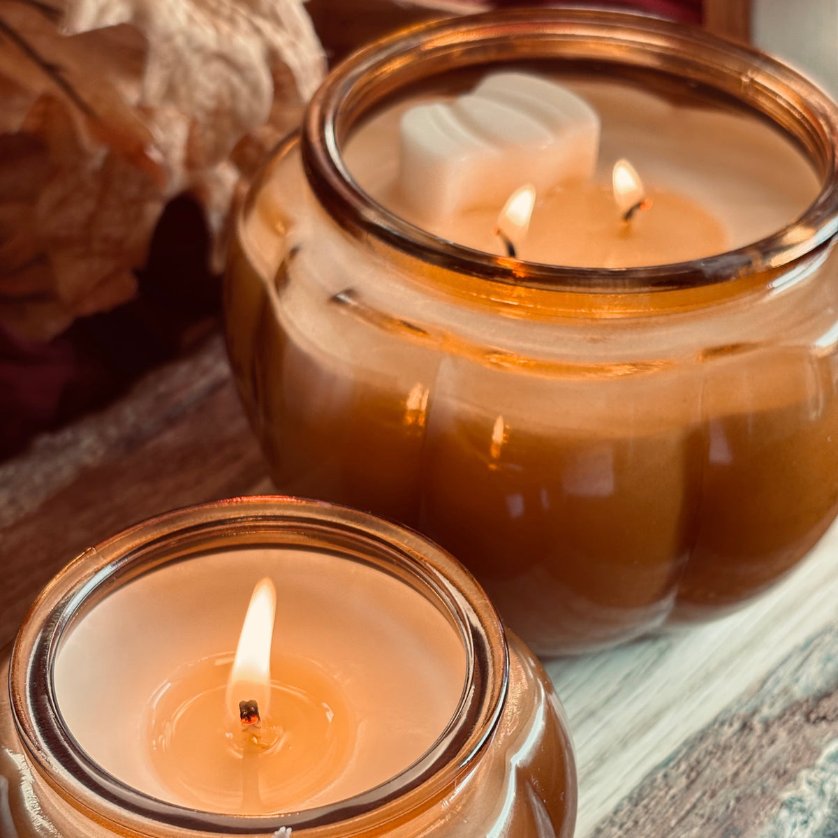 Amber soy candle in glass jar with lit wicks, paired with another candle in background