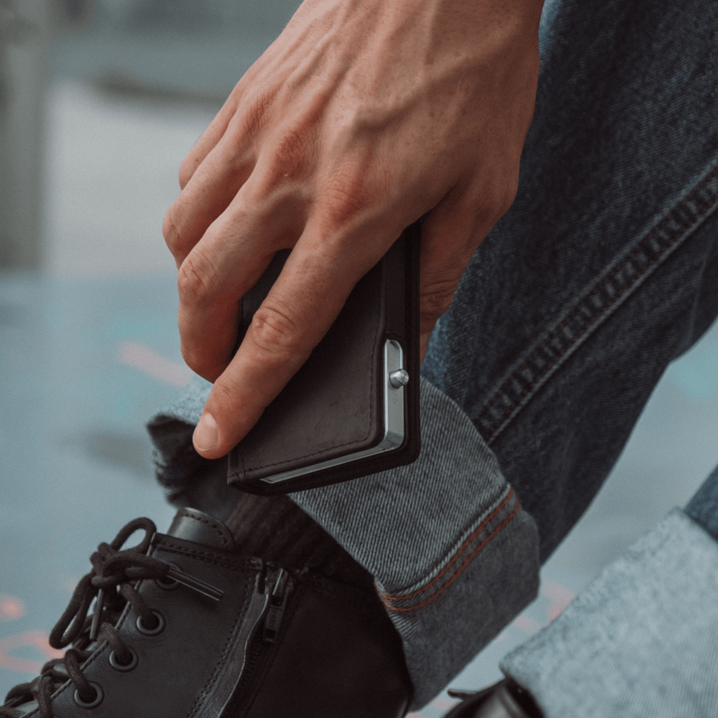 Bifold wallet with dark cover and front snap, held in a hand