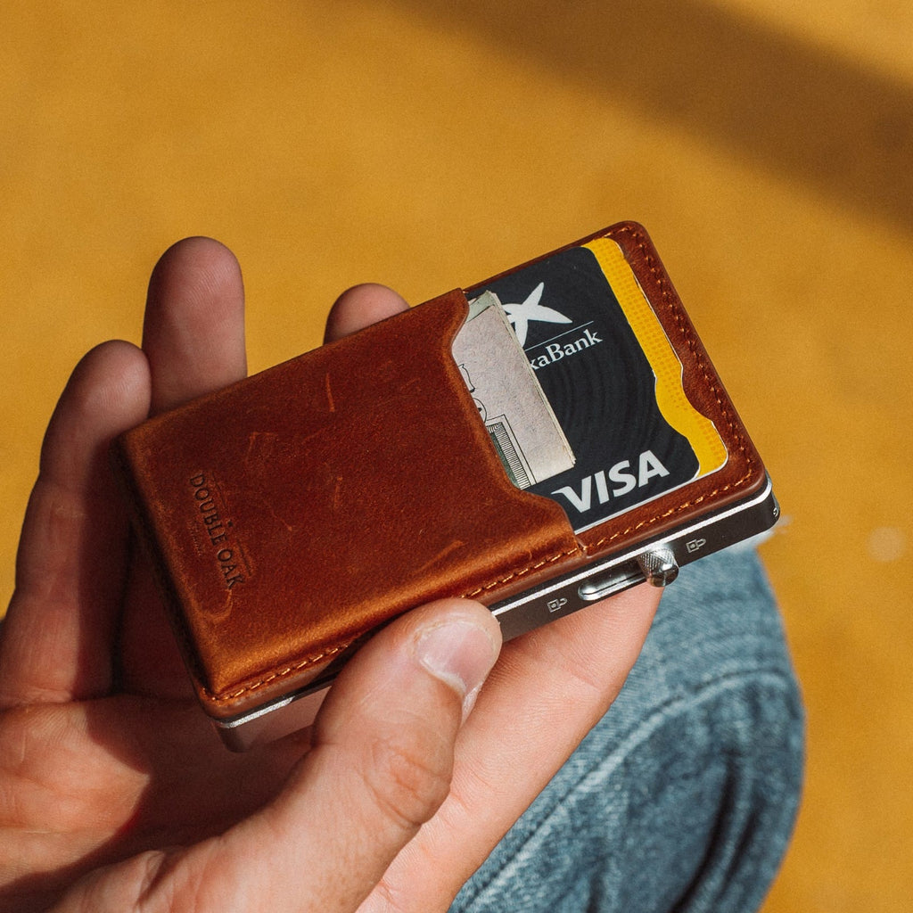 Brown leather mod wallet with card slots and metal clip, held in a hand