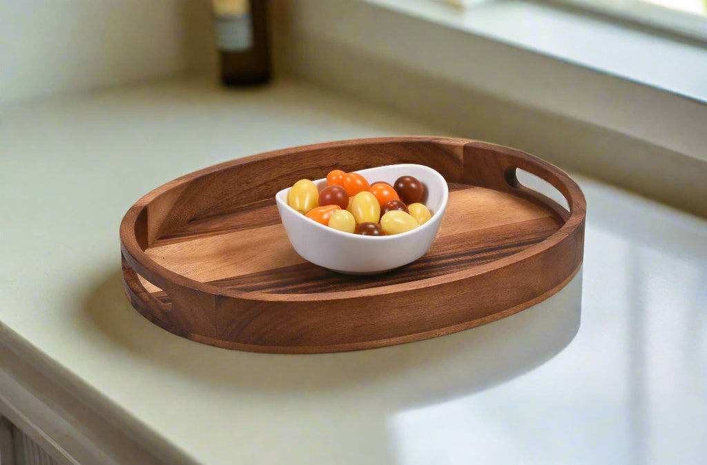 Oval wooden serving tray with cutout handle, holding a bowl of mixed nuts