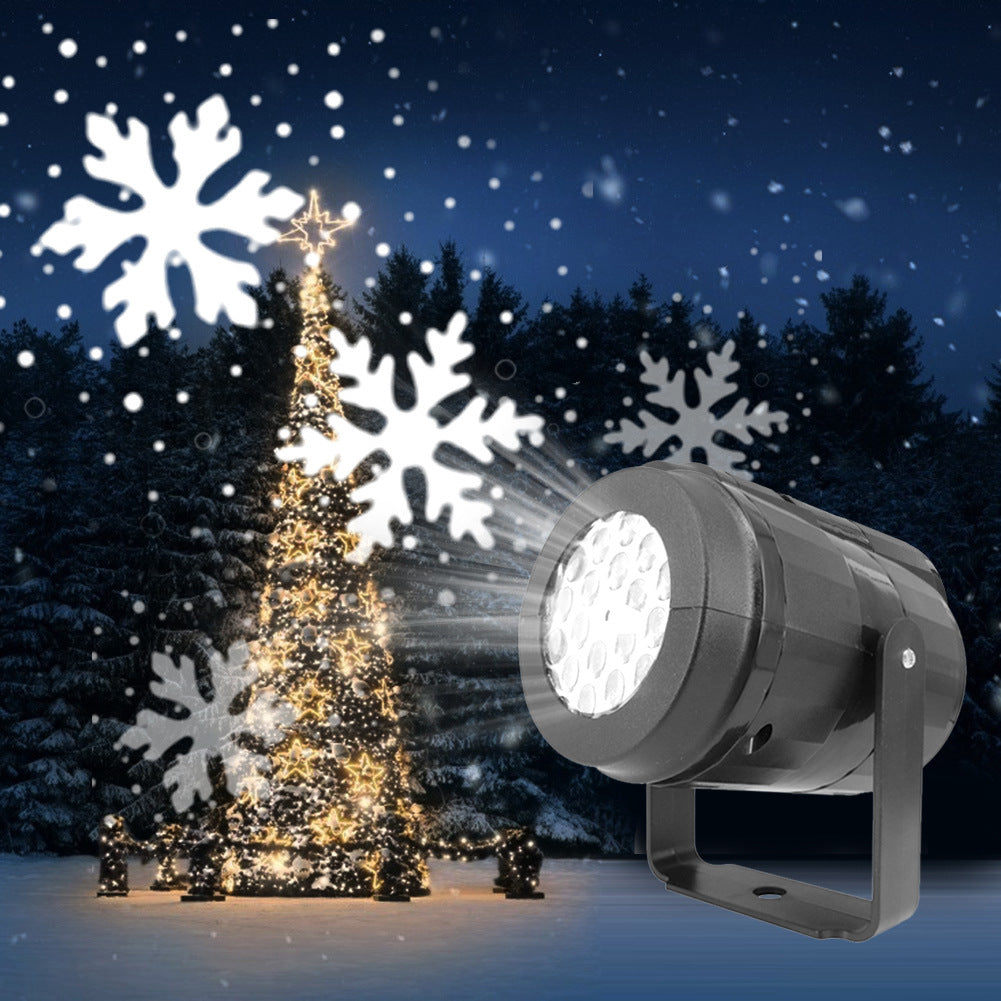 Black LED snowflake projector light casting bright white snowflake dots over snowy trees