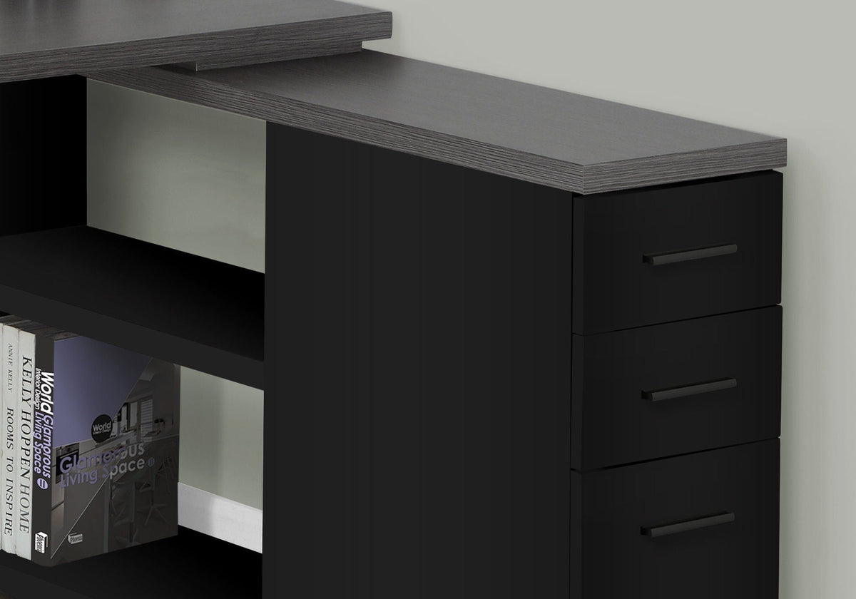 Black corner desk close-up showing drawer fronts and open center shelving.