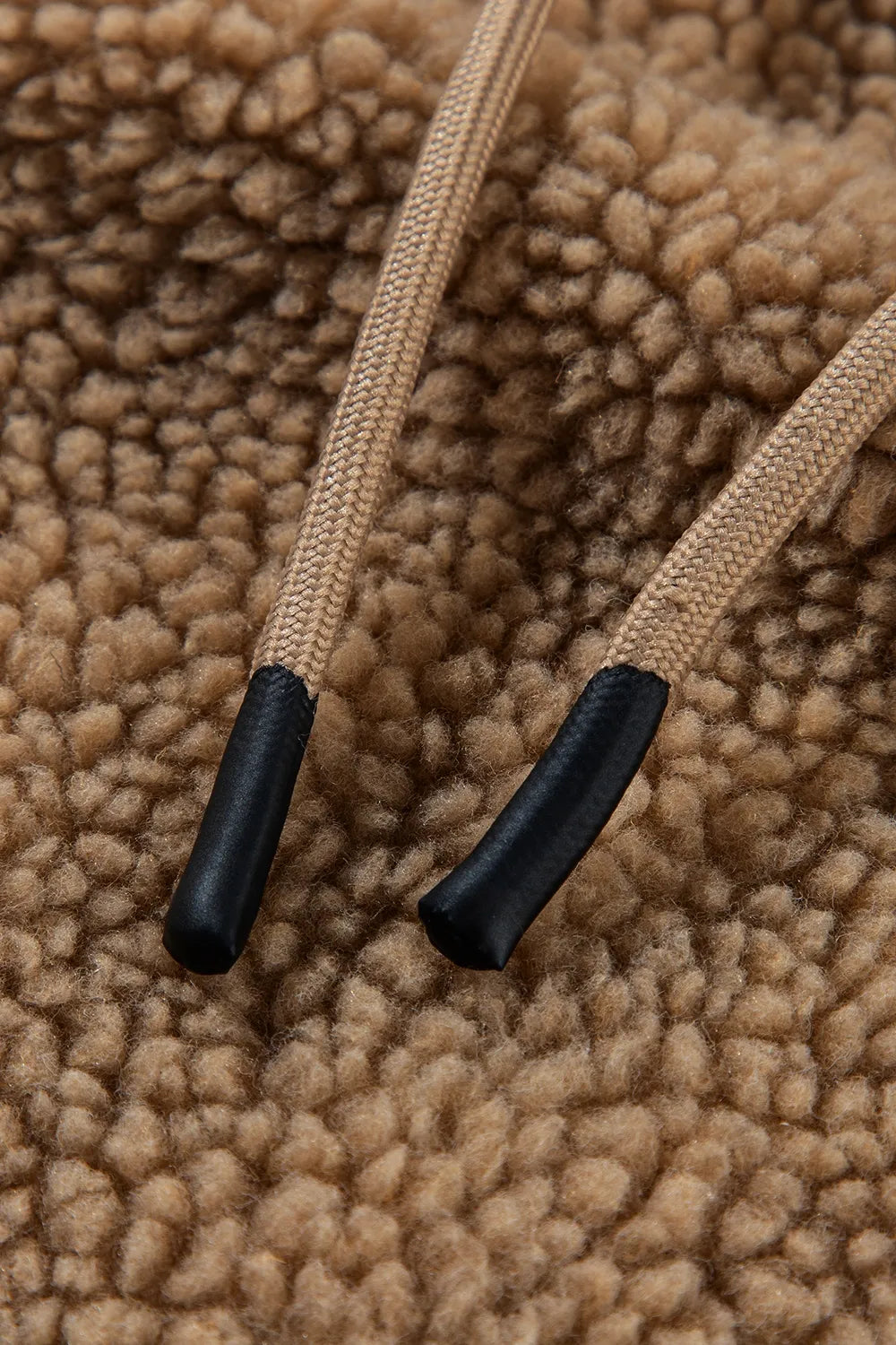 Khaki hood drawstrings with black end caps, close-up