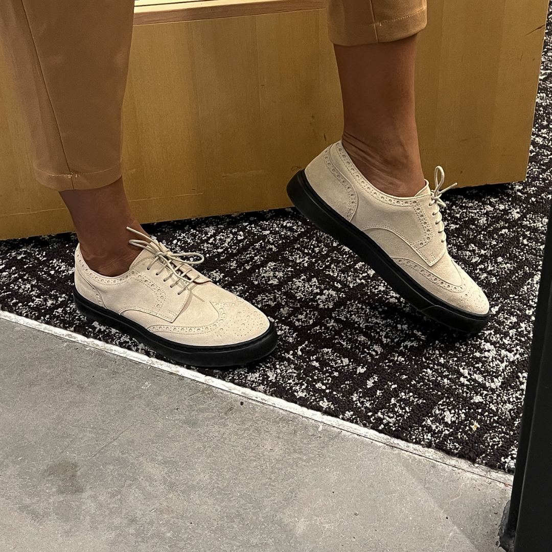 Ivory lace-up oxford shoes with black soles, side view on feet
