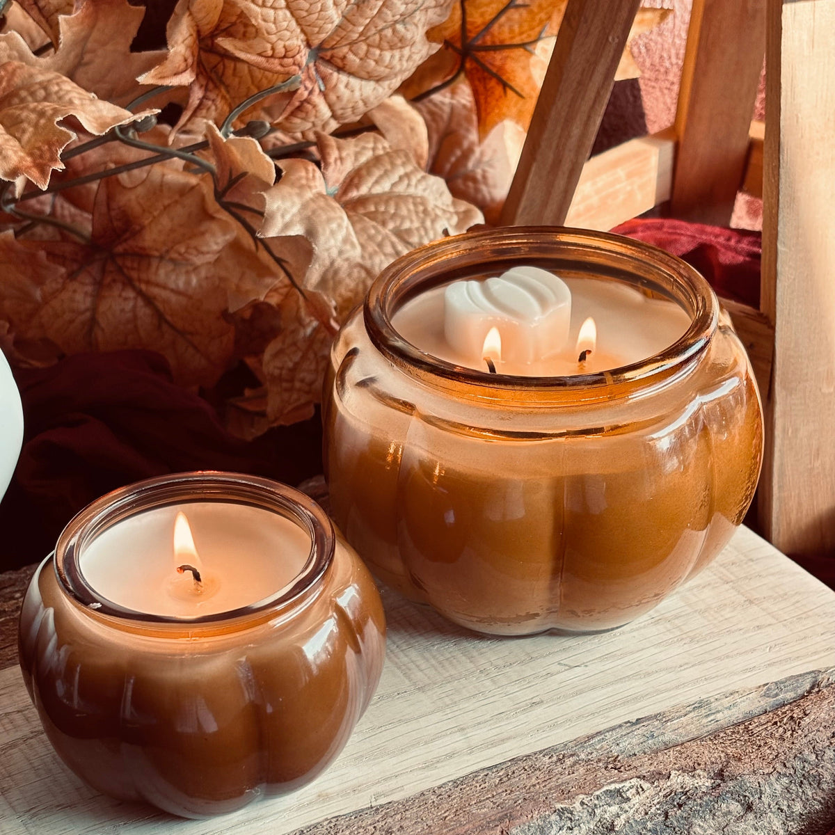 Amber soy candle in round glass jar with lit wicks and white wax swirl lid
