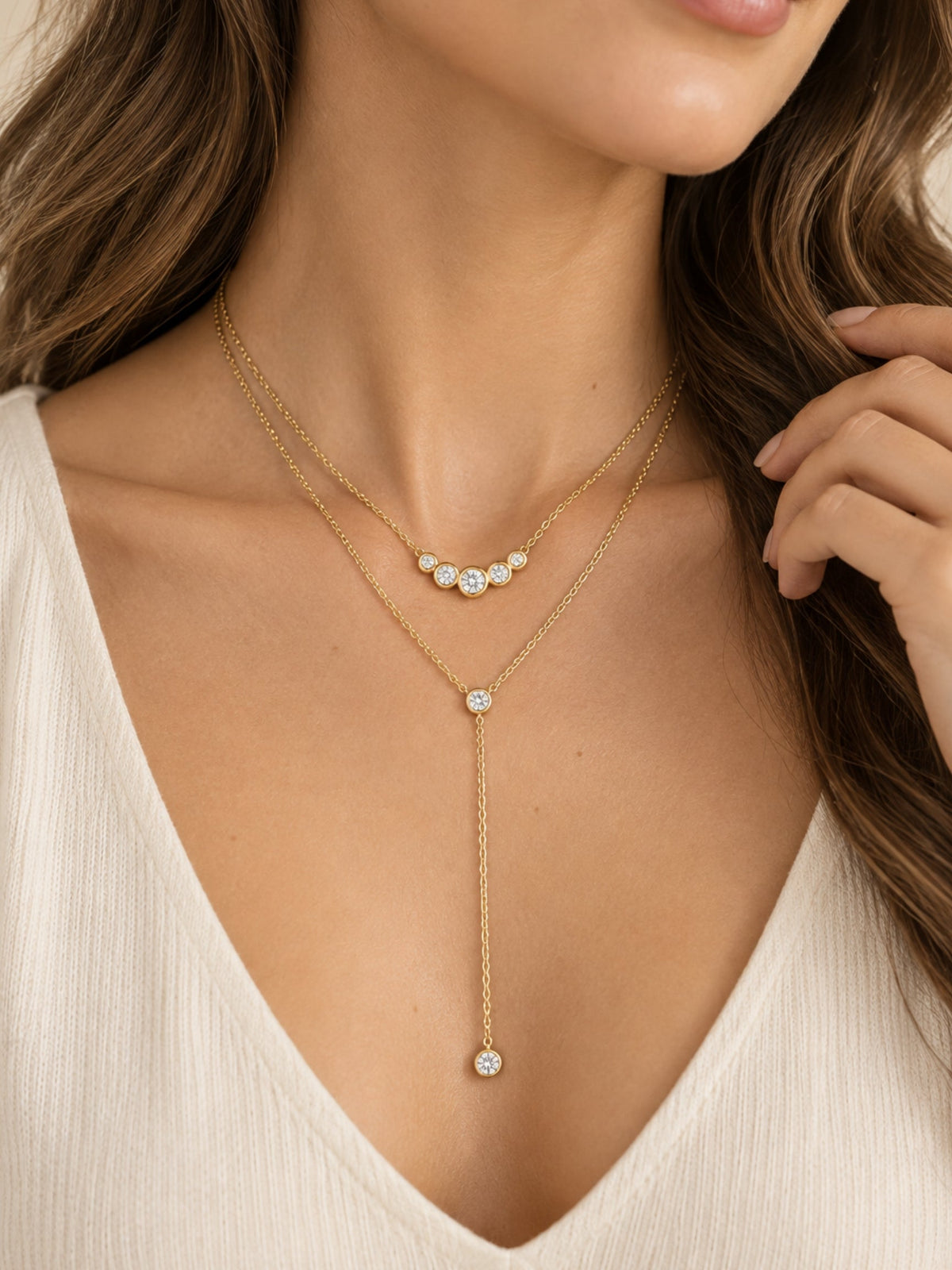 Gold-tone lariat necklace featuring round bezel stones and long drop charm