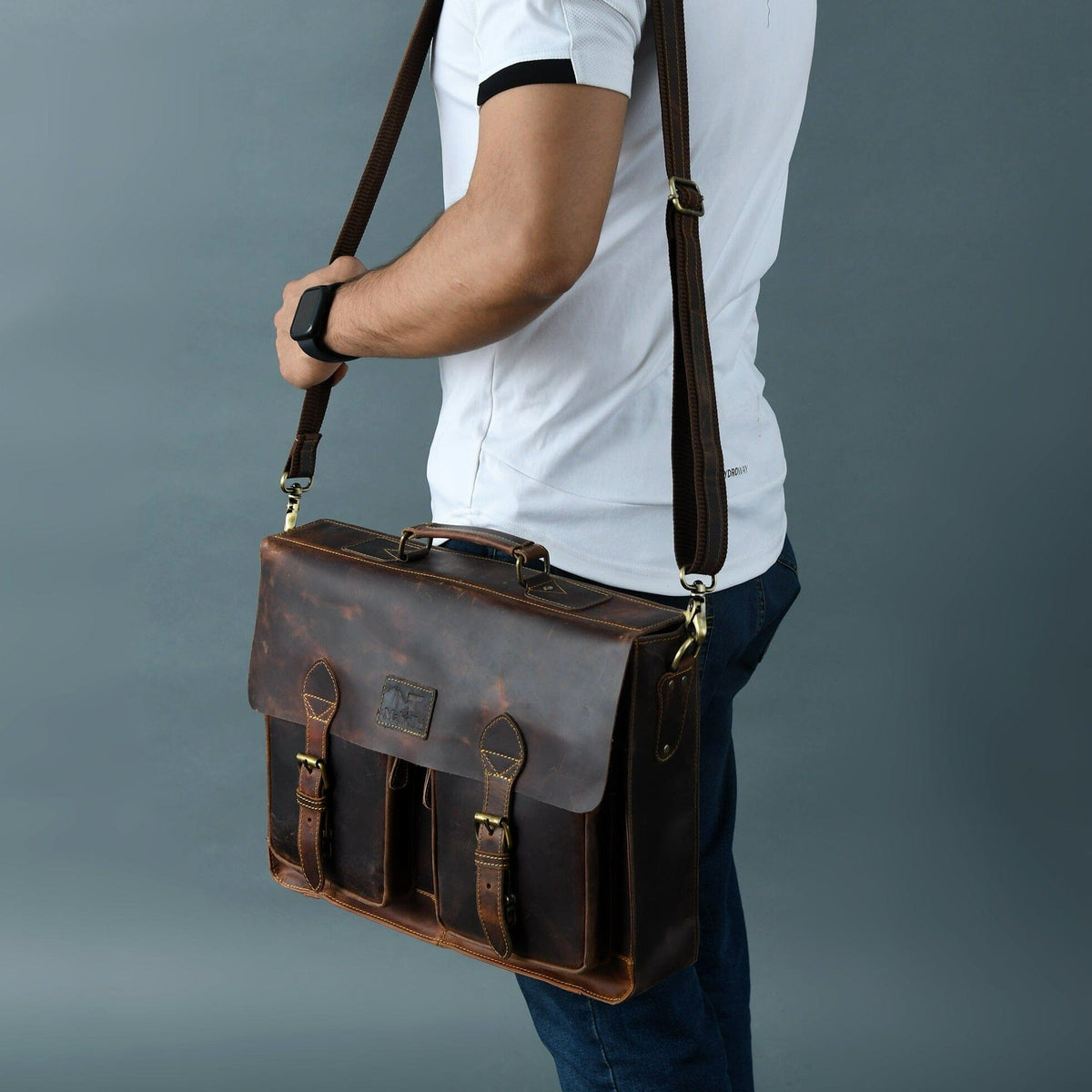 Brown leather briefcase worn crossbody, with flap front and shoulder strap.