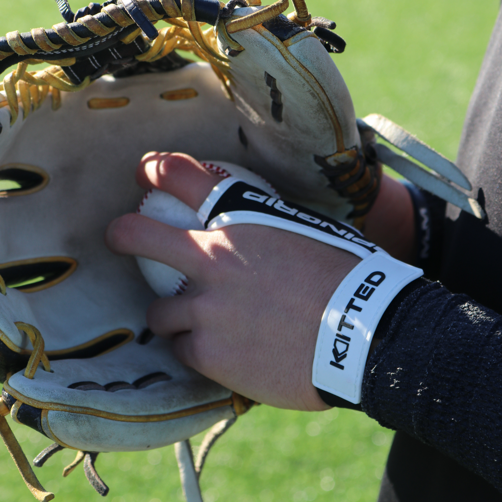 Hand gripping inside a baseball glove with a white baseball