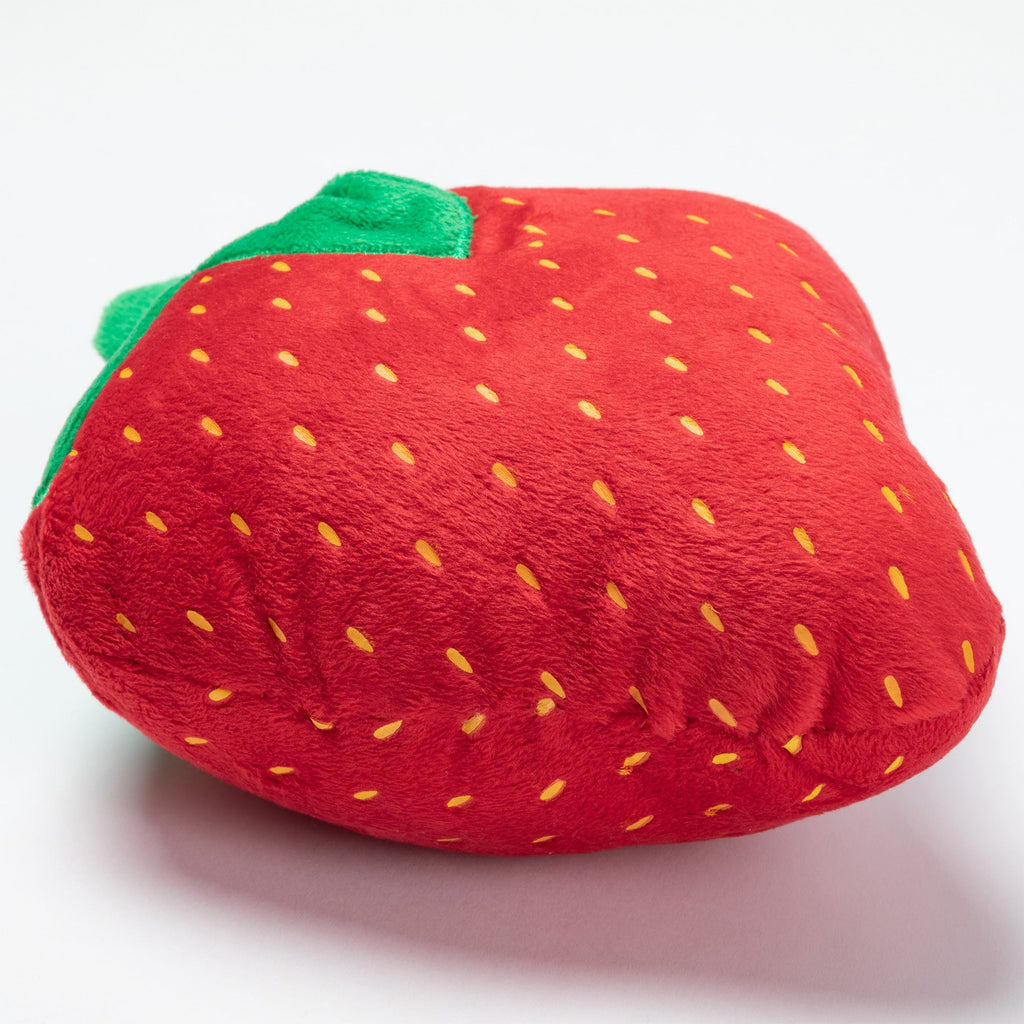 Plush strawberry dog toy close-up, red fabric with yellow seed dots and green leaves.