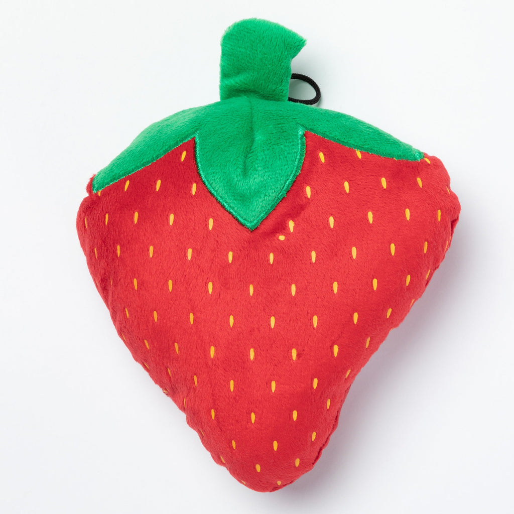 Plush strawberry squeaker toy with green stem and leafy top, yellow seed pattern.