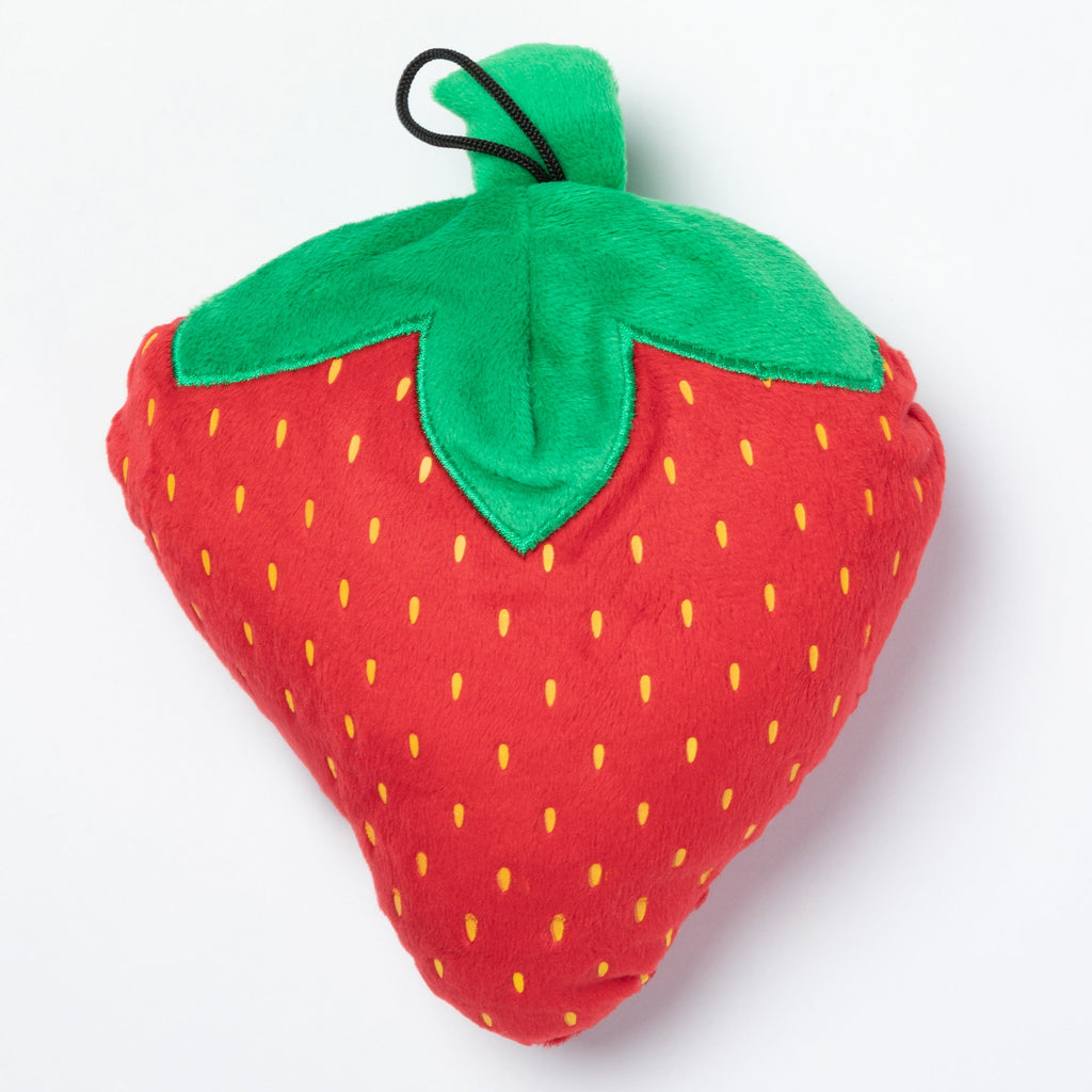 Plush strawberry dog toy with green leafy top, curled black loop, and yellow seed dots.