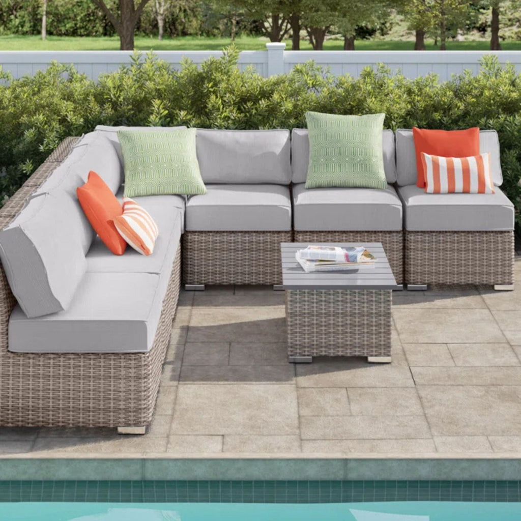 Wicker sectional sofa with gray cushions and square coffee table with throw pillows