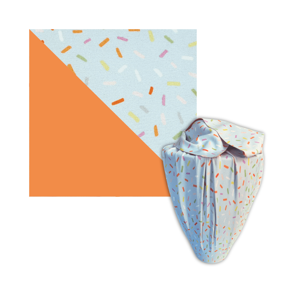 Light blue confetti-pattern reusable furoshiki wrap with tied knot and orange accents