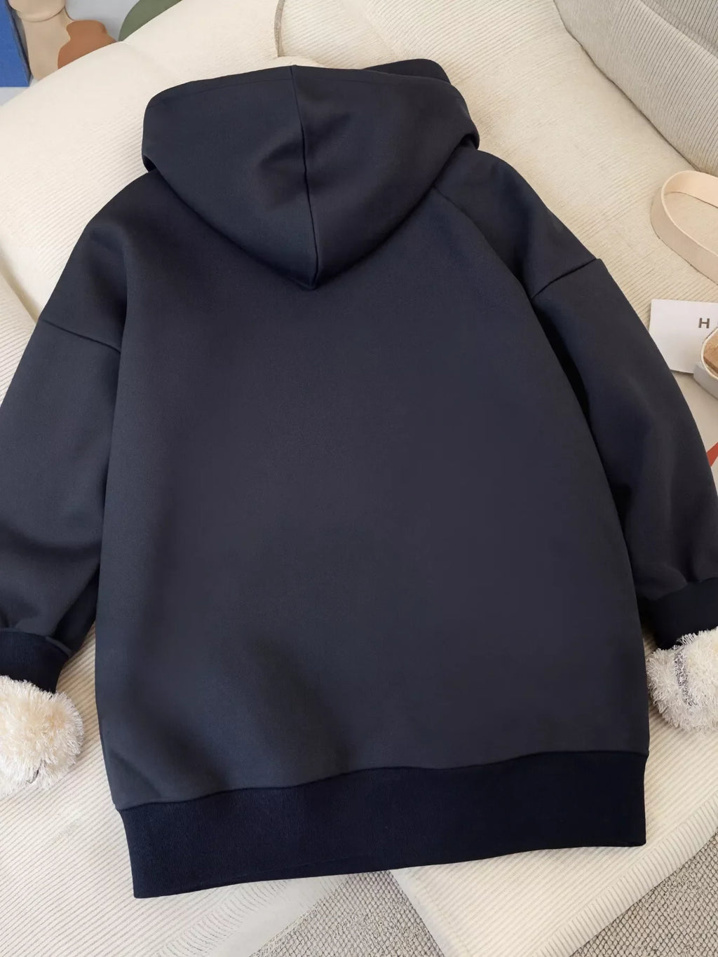 Dark navy fleece-lined zip-up hoodie back view with hood and sherpa trim at cuffs.