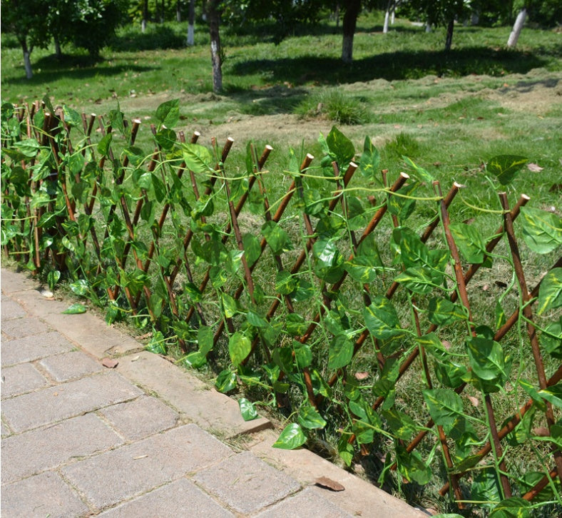 Expandable wooden plant trellis fence with dense green leaves on brown stakes