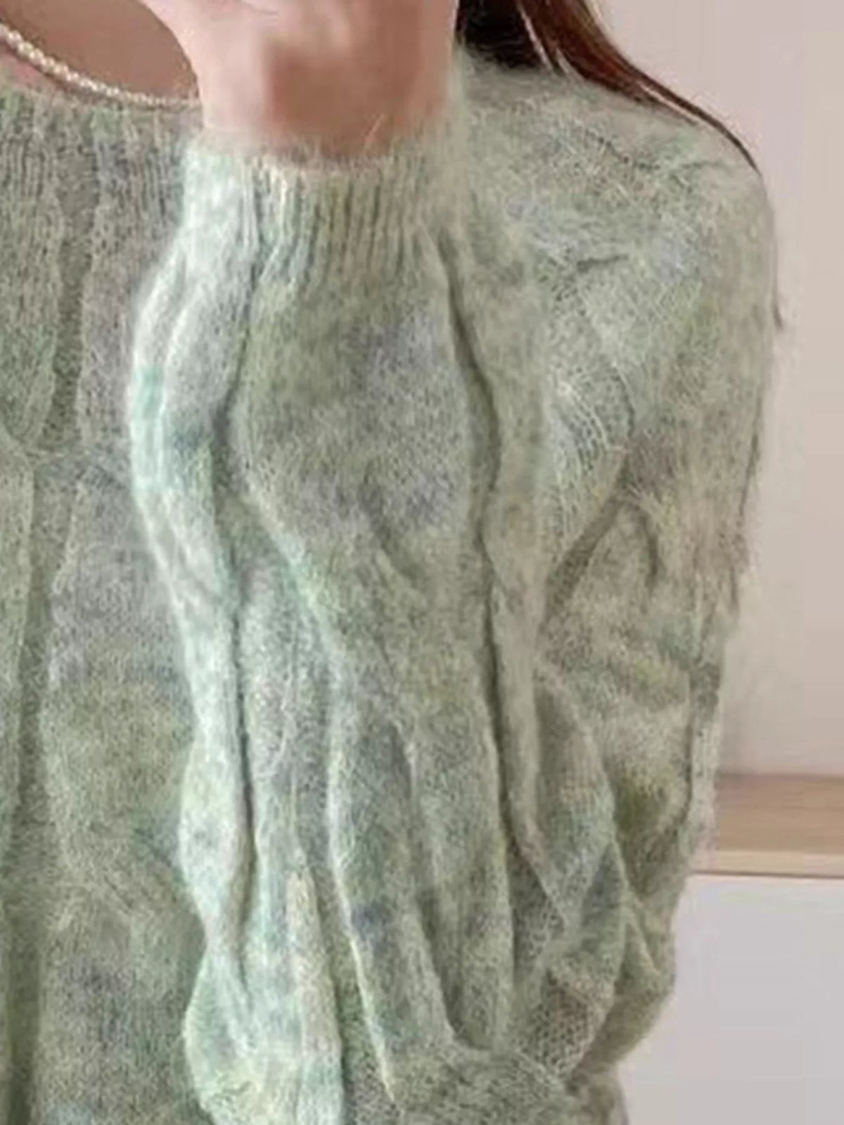 Green cable-knit round neck sweater with long sleeves and ribbed neckline