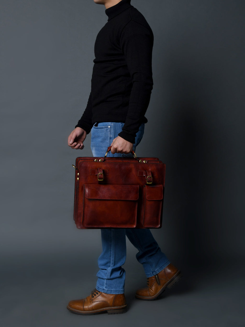Tan leather briefcase held by handle with front flap and front side pocket.