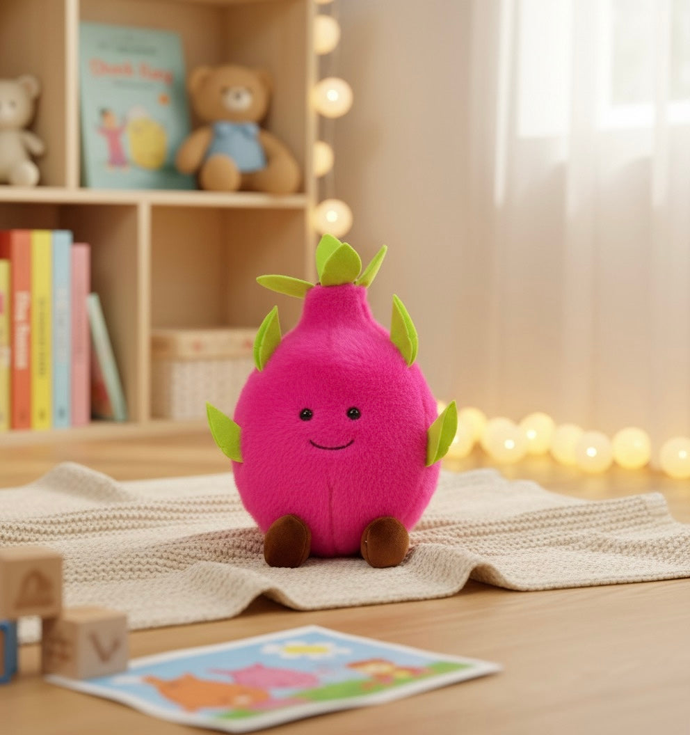 Pink dragon fruit plush toy with green leaves and stitched smile on a blanket