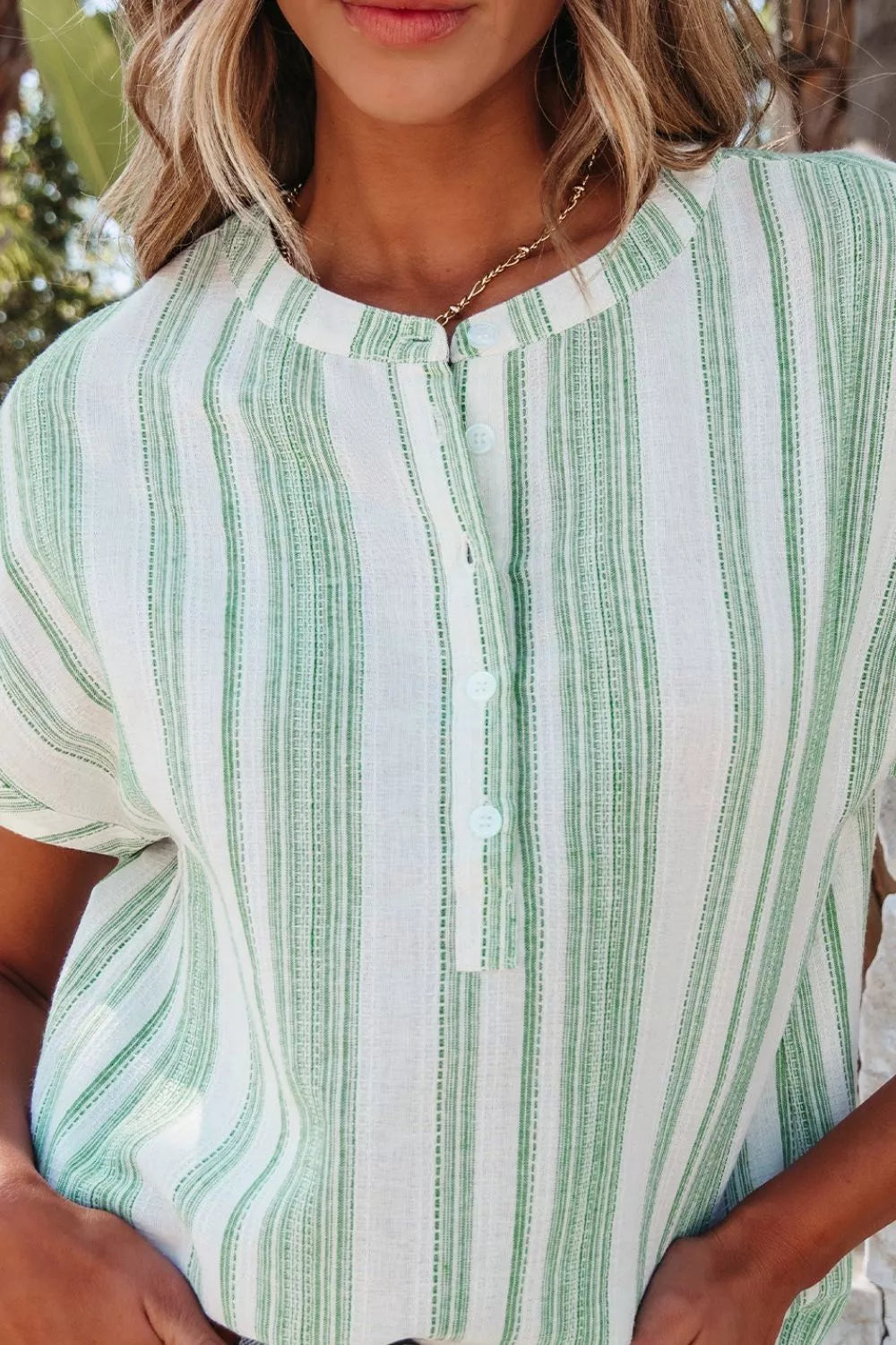 Light green striped gauze blouse close-up with half-button placket and short sleeves