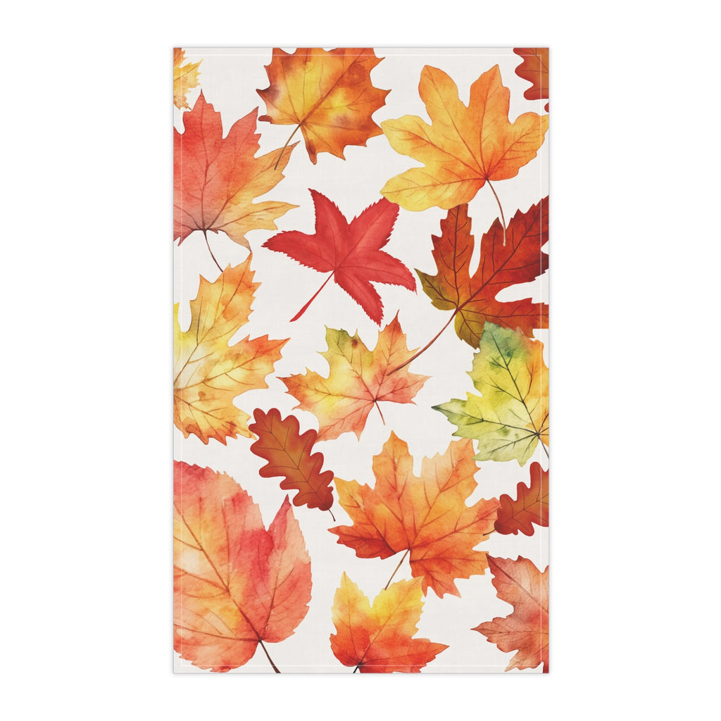 Tea towel featuring scattered fall leaves in red, orange, yellow, and green on white