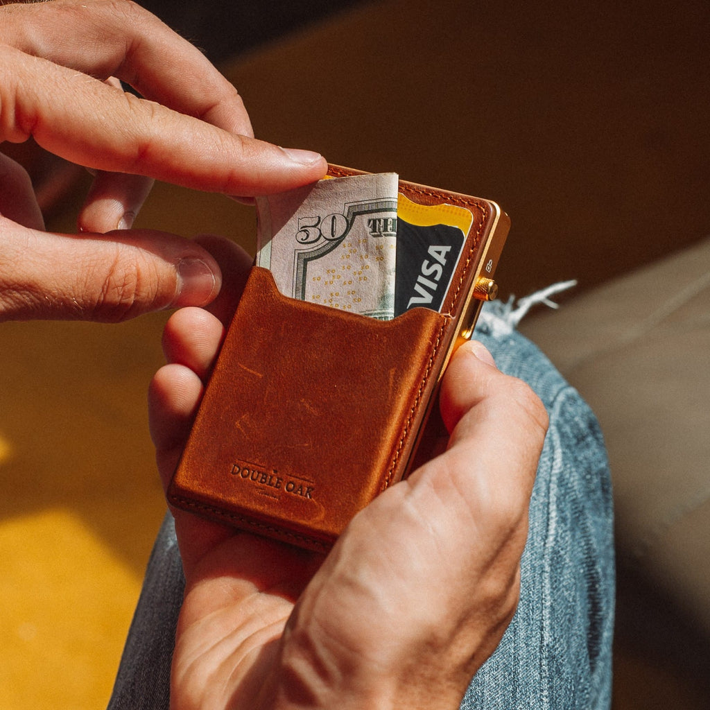 Brown leather card wallet with Visa card and gold frame, hand adjusting the card