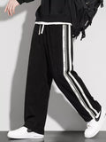 Black loose-fit casual pants with vertical white striped side panels and drawstring waist