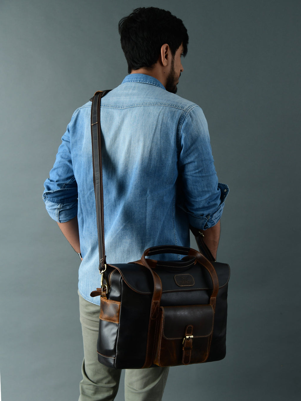 Black-brown leather briefcase bag worn with shoulder strap and top carry handle