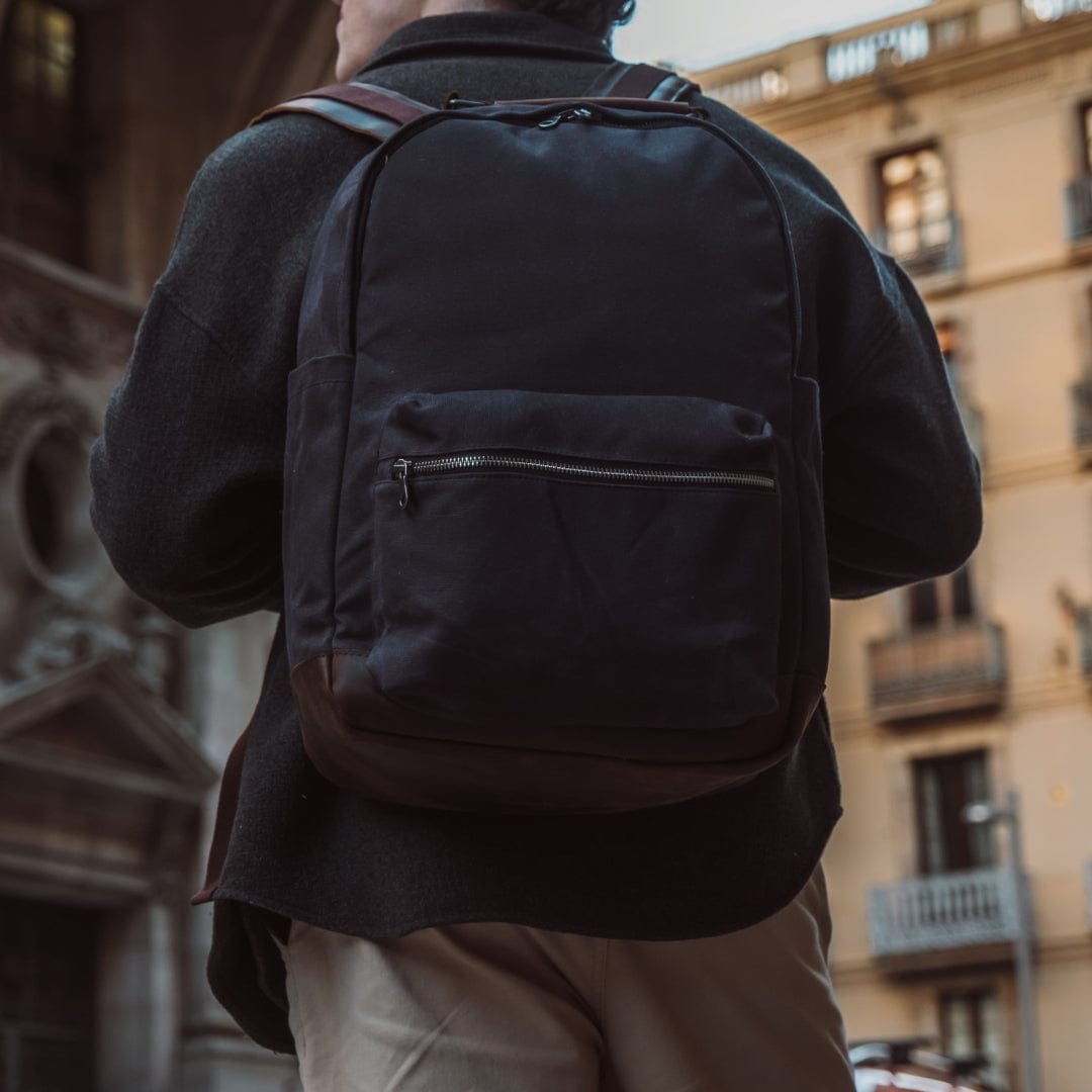 Dark backpack with back panel and front zip pocket detail