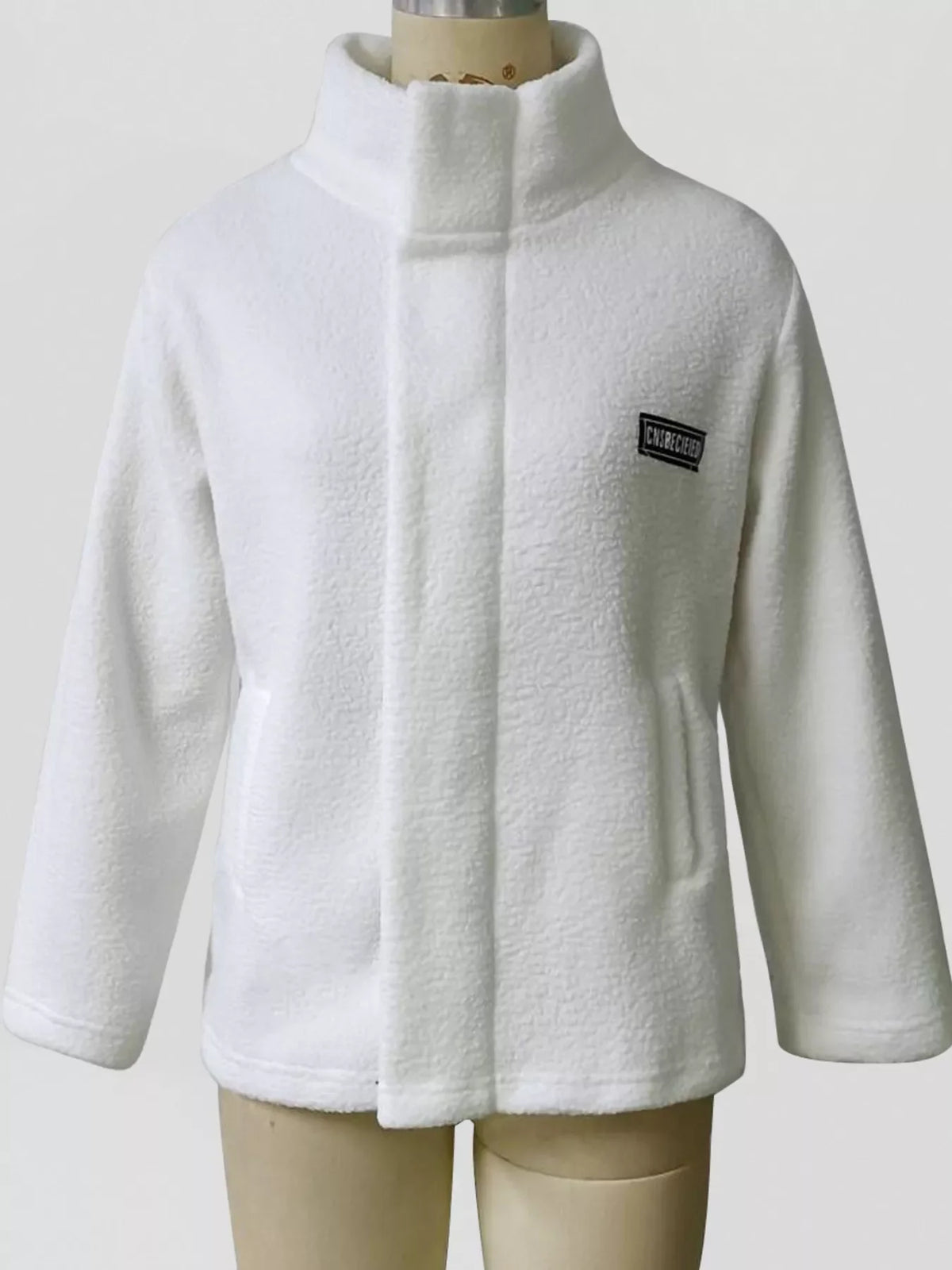 White sherpa fleece zip-up jacket on mannequin with stand collar and logo patch