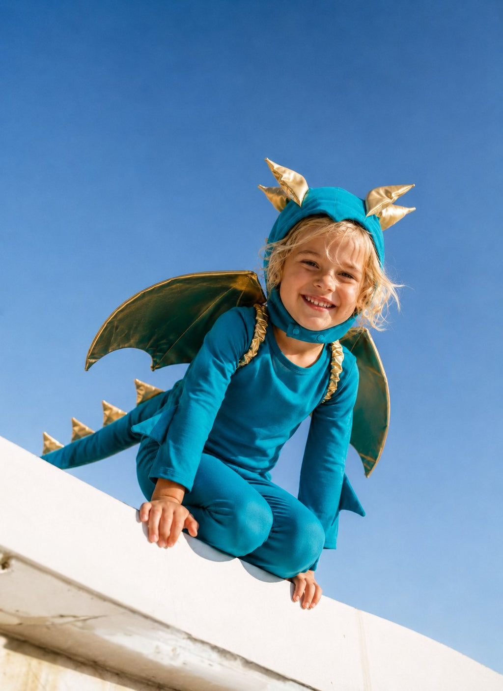 Turquoise dragon costume with gold-trim wings and headpiece, toddler in jumpsuit and cape.