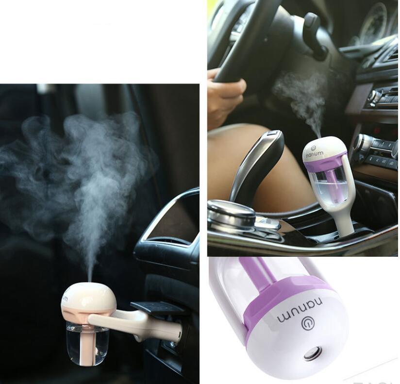Purple mini car aroma diffuser releasing mist from the clear tank