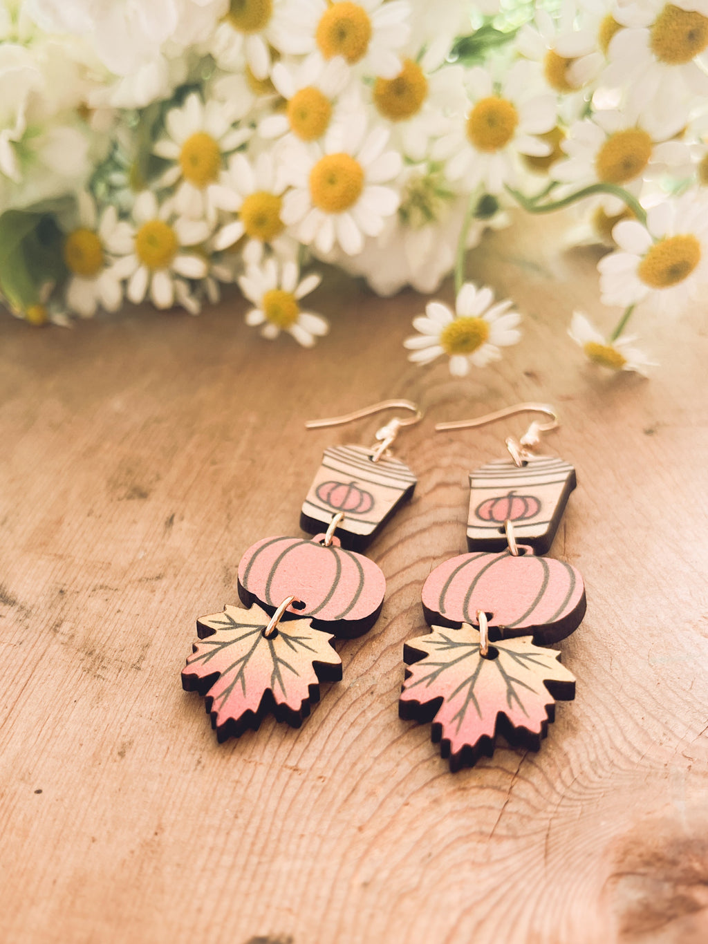 Close view of wood earrings with coffee cup, pumpkin, and leaf dangles