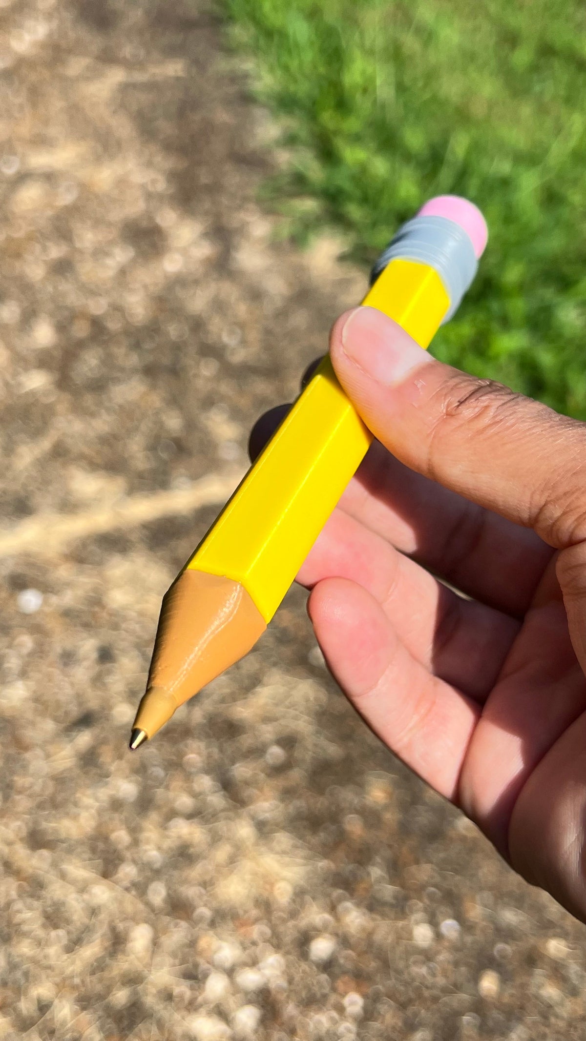 Jumbo yellow pencil close-up with pink eraser, gray striped band, wooden point