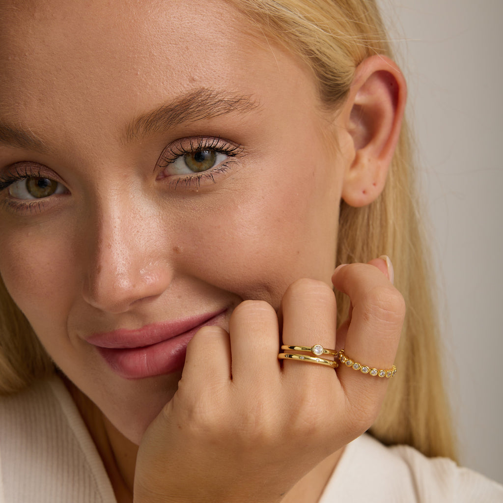 Gold bezel stone ring on finger with round center stone