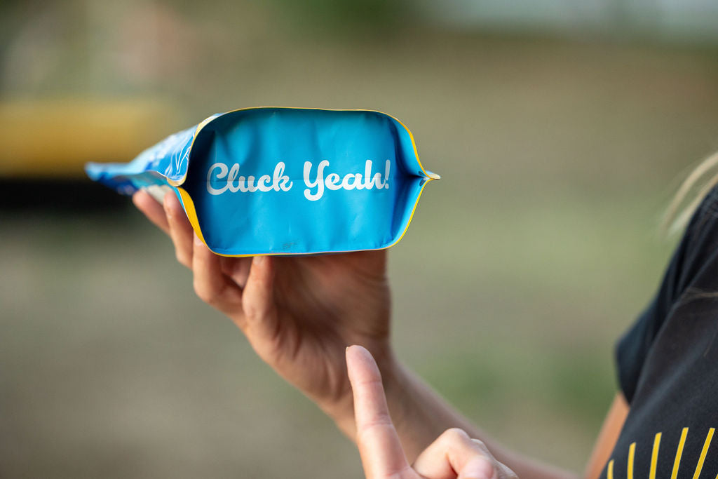 Blue herb supplement pouch with yellow trim held up in front of a person