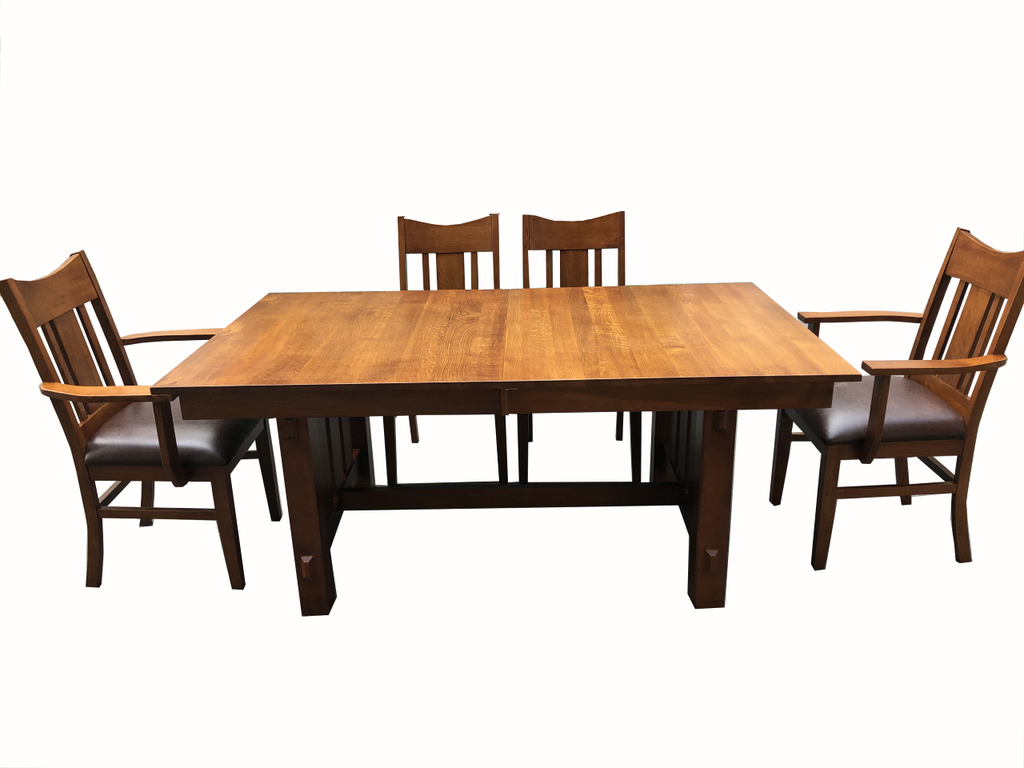 Mission-style dining table with chairs, showing apron and dark upholstered chair seats.
